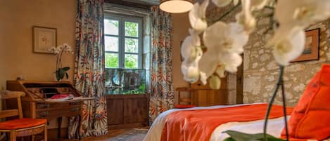 Un dormitorio con cama, escritorio, silla, ventana con cortinas y una lámpara colgante.