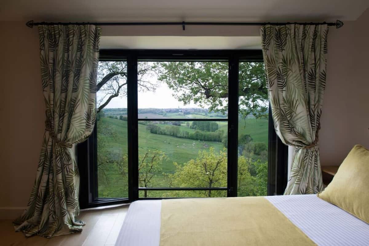 Une chambre avec une grande fenêtre, un lit et des rideaux.