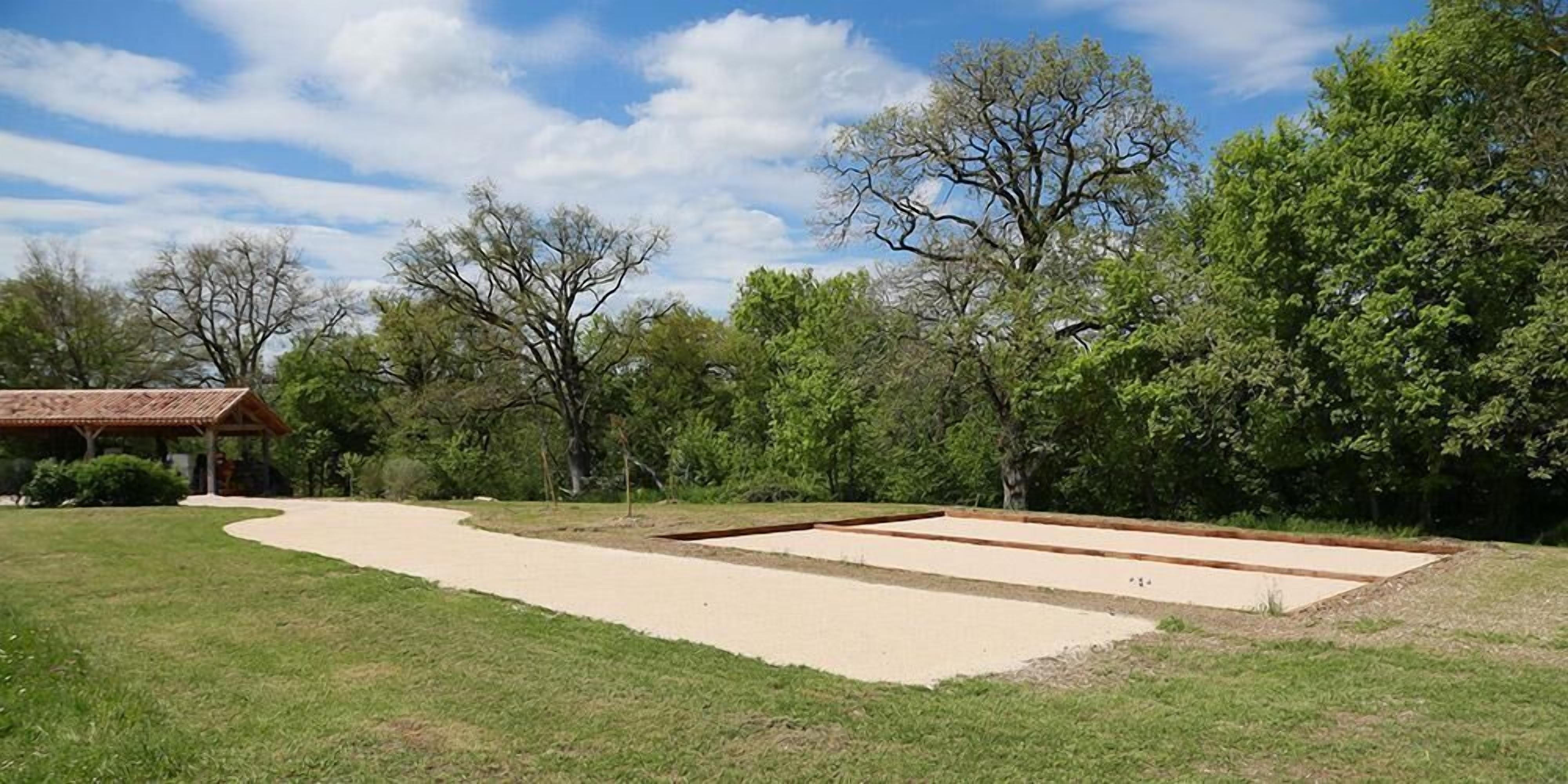 Un parque con un arenero, un pabellón y árboles.