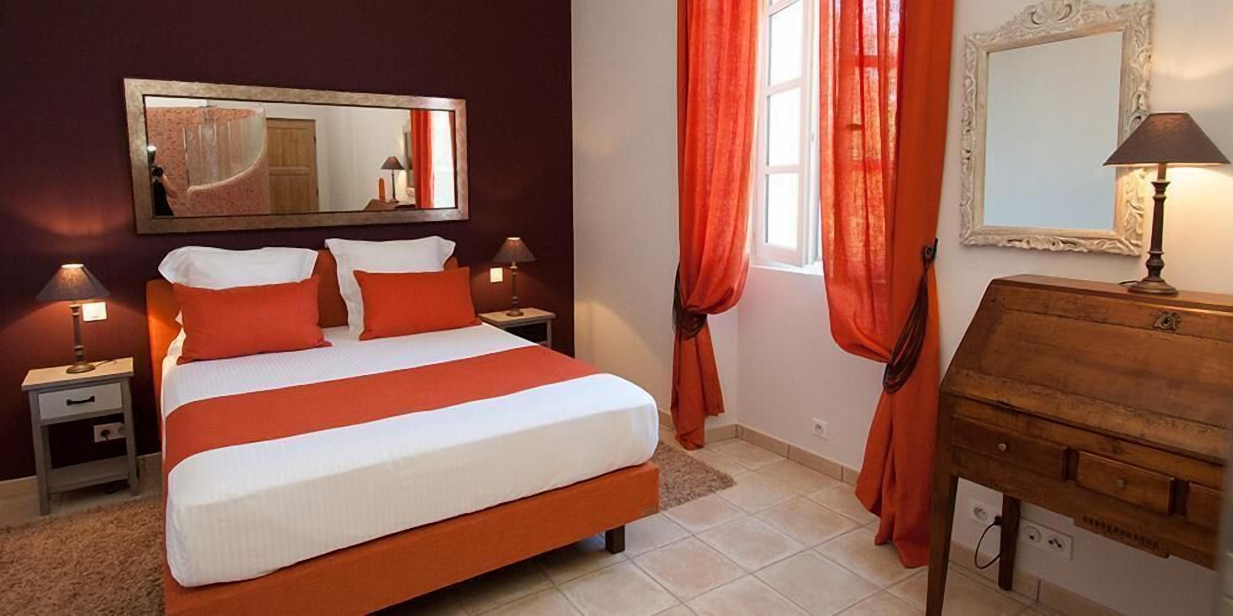 A hotel room with a bed, nightstands, a dresser, and a mirror.