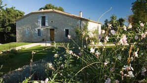 Une maison en pierre avec un toit en tuiles, une porte d’entrée et un petit porche.
