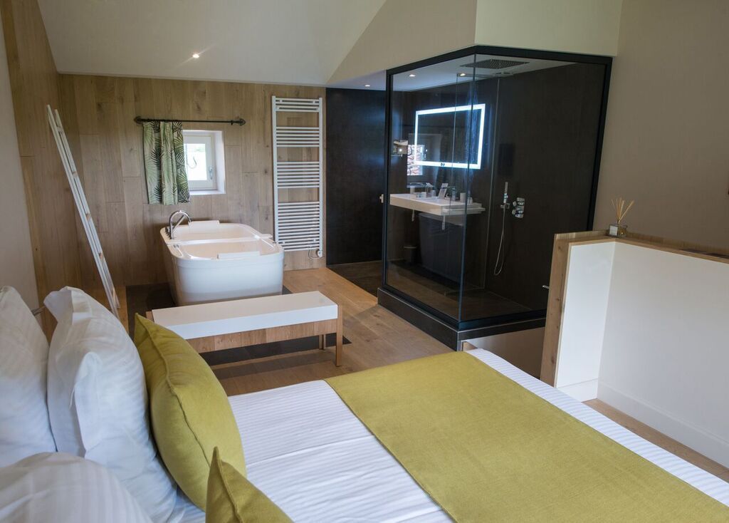 Un dormitorio moderno con una cama grande, un vestidor, un baño separado con bañera y cabina de ducha acristalada.