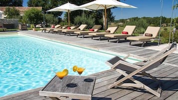 Alberca techada, alberca al aire libre y sombrillas en la alberca