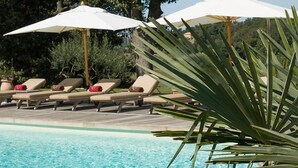 Un espace aménagé au bord de la piscine, avec des chaises longues et des parasols.