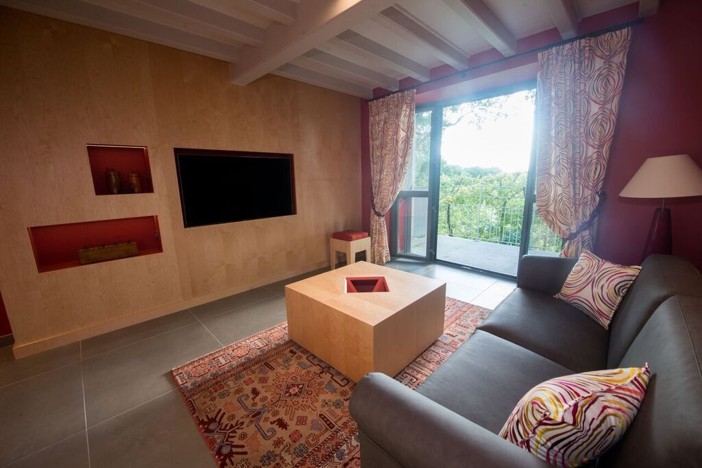 Una sala de estar moderna con un sofá, una mesita de centro, un televisor de pantalla plana y un amplio ventanal con cortinas.
