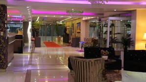 A hotel lobby with a red carpet, seating area, and a reception desk. - Hotel Luxsur (Encarnacion)