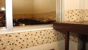 A corner of a room with a tiled backsplash and a window overlooking a cityscape at night. - Hotel Luxsur (Encarnacion)
