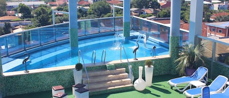 Una piscina al aire libre, sillones reclinables de piscina