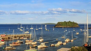 A marina with numerous boats docked, a pier, and a small island with trees in the background. - 16 Bay View (Camden)