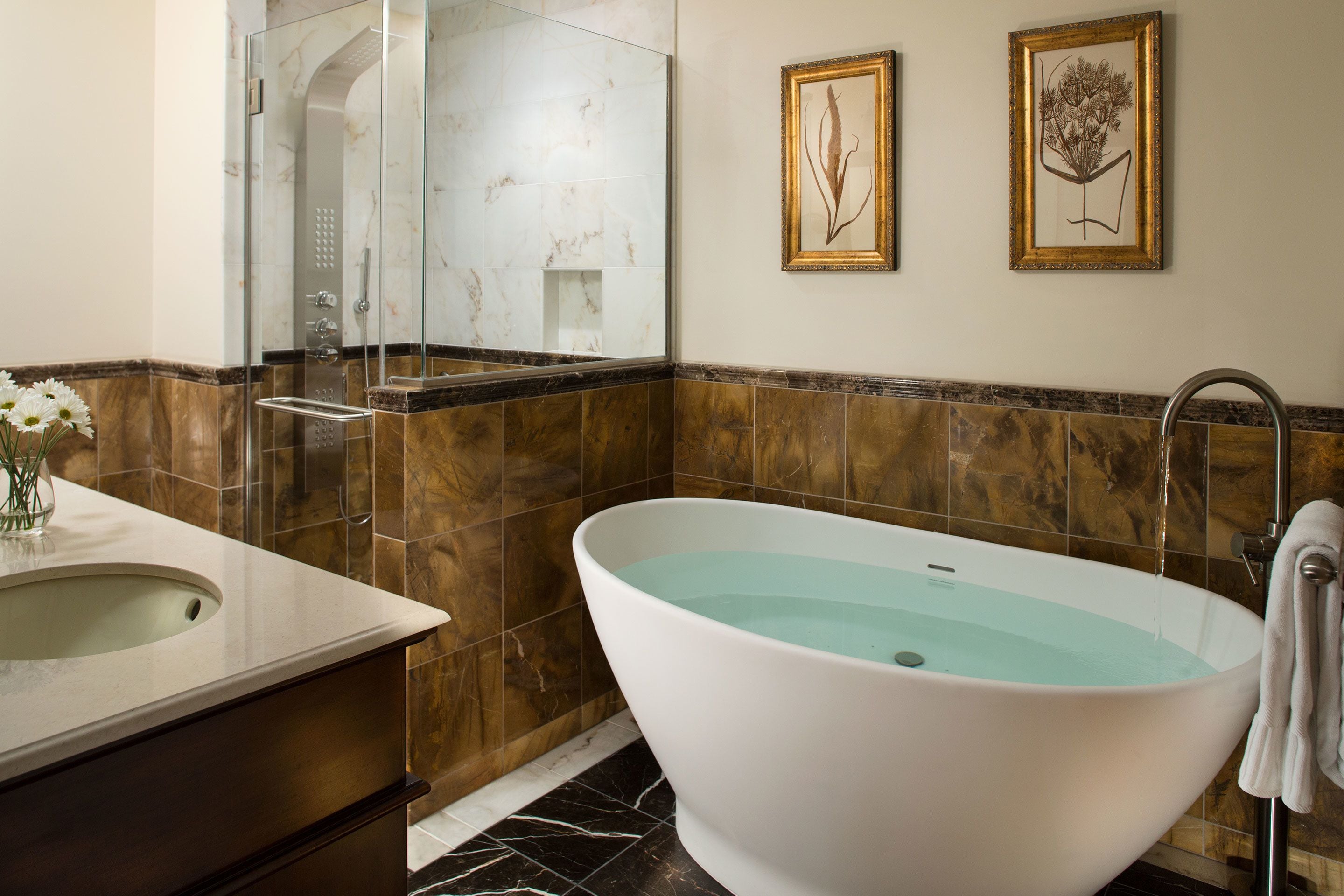 A bathroom with a freestanding bathtub, a sink, and a shower area.
