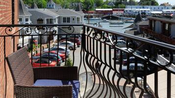 A balcony with wicker furniture overlooking a marina with boats and a parking area.