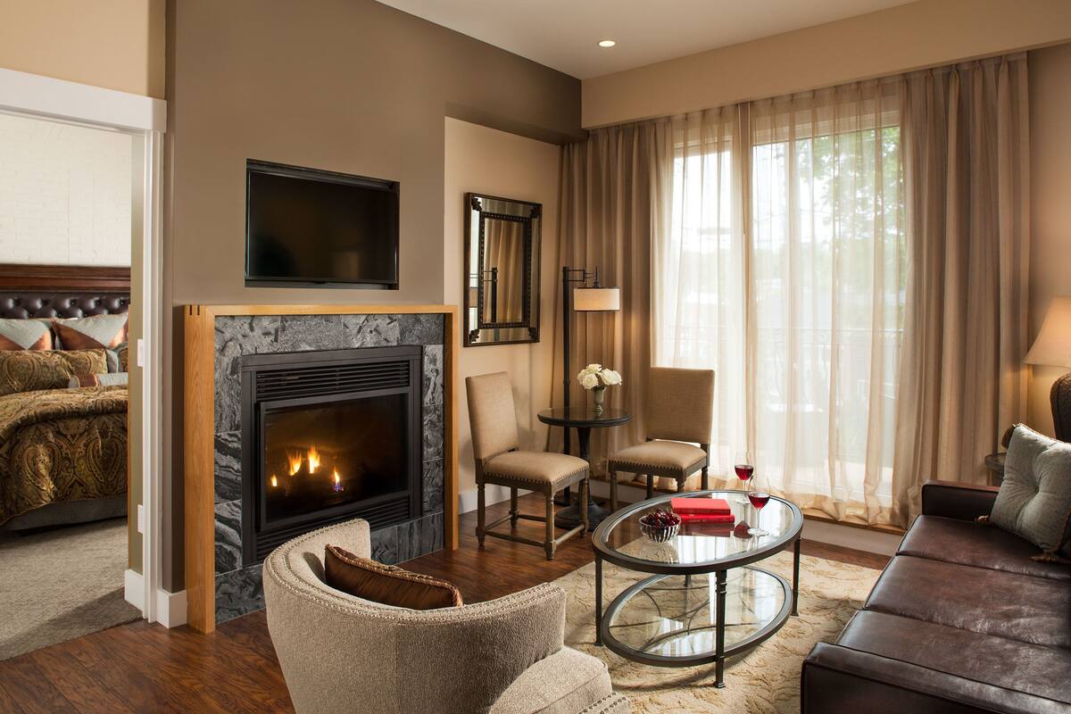 A modern living room with a fireplace, comfortable seating, and a large window with curtains.
