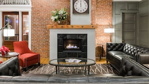 A cozy living room with a fireplace, leather furniture, and a clock on the wall. - 16 Bay View (Camden)
