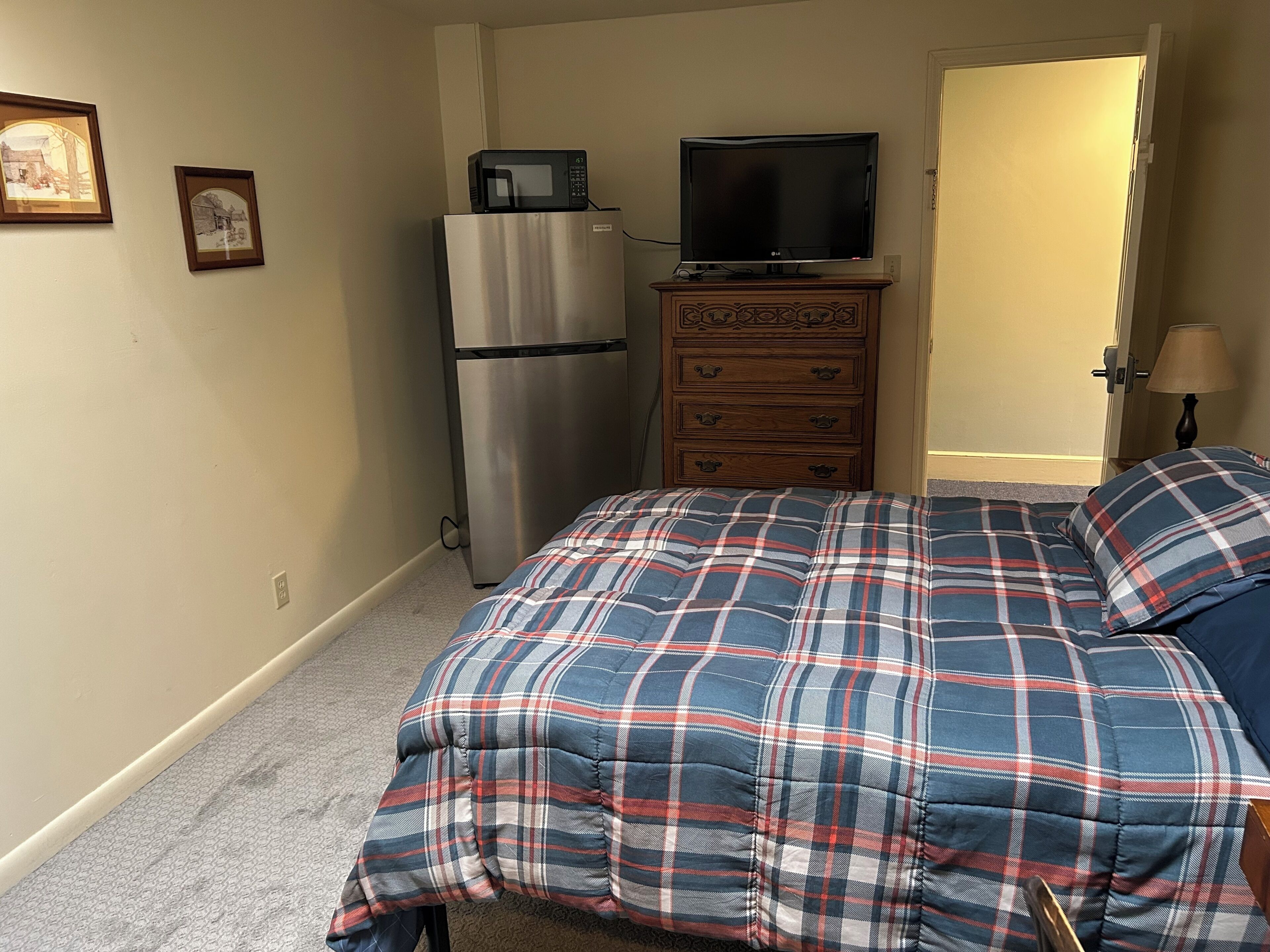 Un dormitorio con cama, cómoda, microondas y televisor.