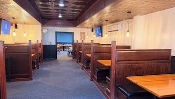 A restaurant interior with booths and tables, wooden ceiling, and wall-mounted TVs.