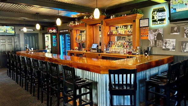 A bar with a wooden counter, black bar stools, and a neon sign. - The Inn at Montrose (Montrose)