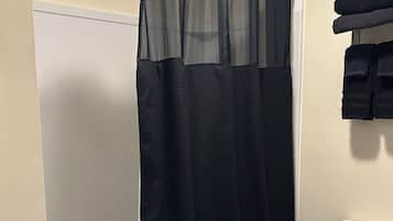 A bathroom with a shower curtain, a toilet, and a towel rack.
