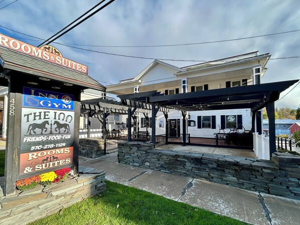 A hotel with a sign for rooms and suites, a gym, and a covered outdoor seating area. - The Inn at Montrose (Montrose)