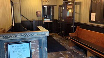 A hotel lobby with a wooden bench, a sign indicating a restroom, and a chandelier.
