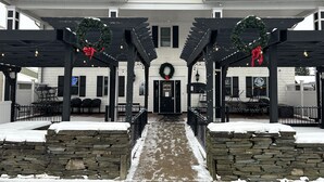 A building with a covered outdoor seating area, stone walls, and a snow-covered ground. - The Inn at Montrose (Montrose)