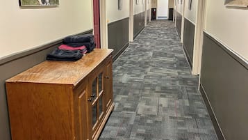 A hallway with a patterned carpet, wooden bench, framed pictures on the walls, and doors leading to rooms.
