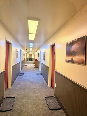 A hotel hallway with carpeted floors, doors on both sides, and a painting on the right wall. - The Montrose Hotel (Montrose)