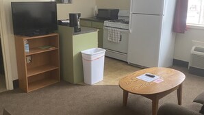 A compact hotel room with a kitchenette, a television, a small dining table, and a sofa. - The Montrose Hotel (Montrose)