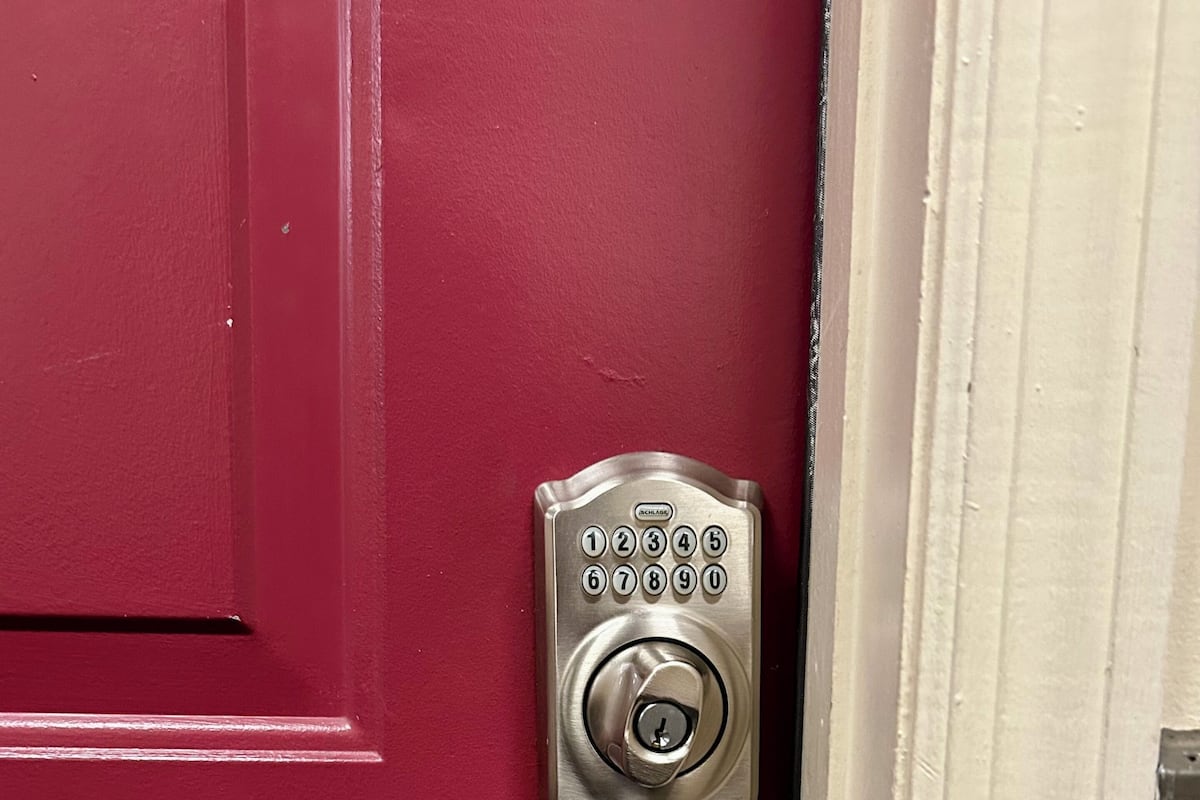 A red door with a numeric keypad lock and a lever handle.