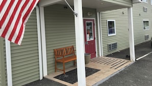A building with a porch, a red door, and a flag. - The Montrose Hotel (Montrose)
