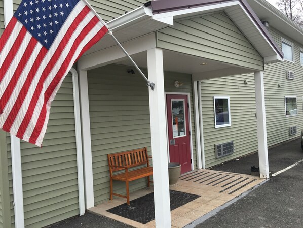 A building with a porch, a red door, and a flag. - The Montrose Hotel (Montrose)