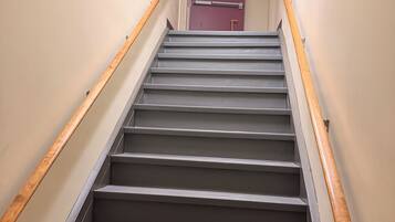 A staircase with wooden handrails and a red door at the top.