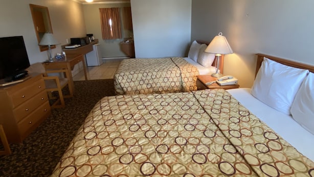 A hotel room with two beds, a desk, a television, and a bathroom visible through an open door. - Aspen Motor Inn (Drayton Valley)