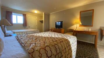 Habitación de hotel con dos camas, televisión, escritorio con lámpara y espejo en la pared.