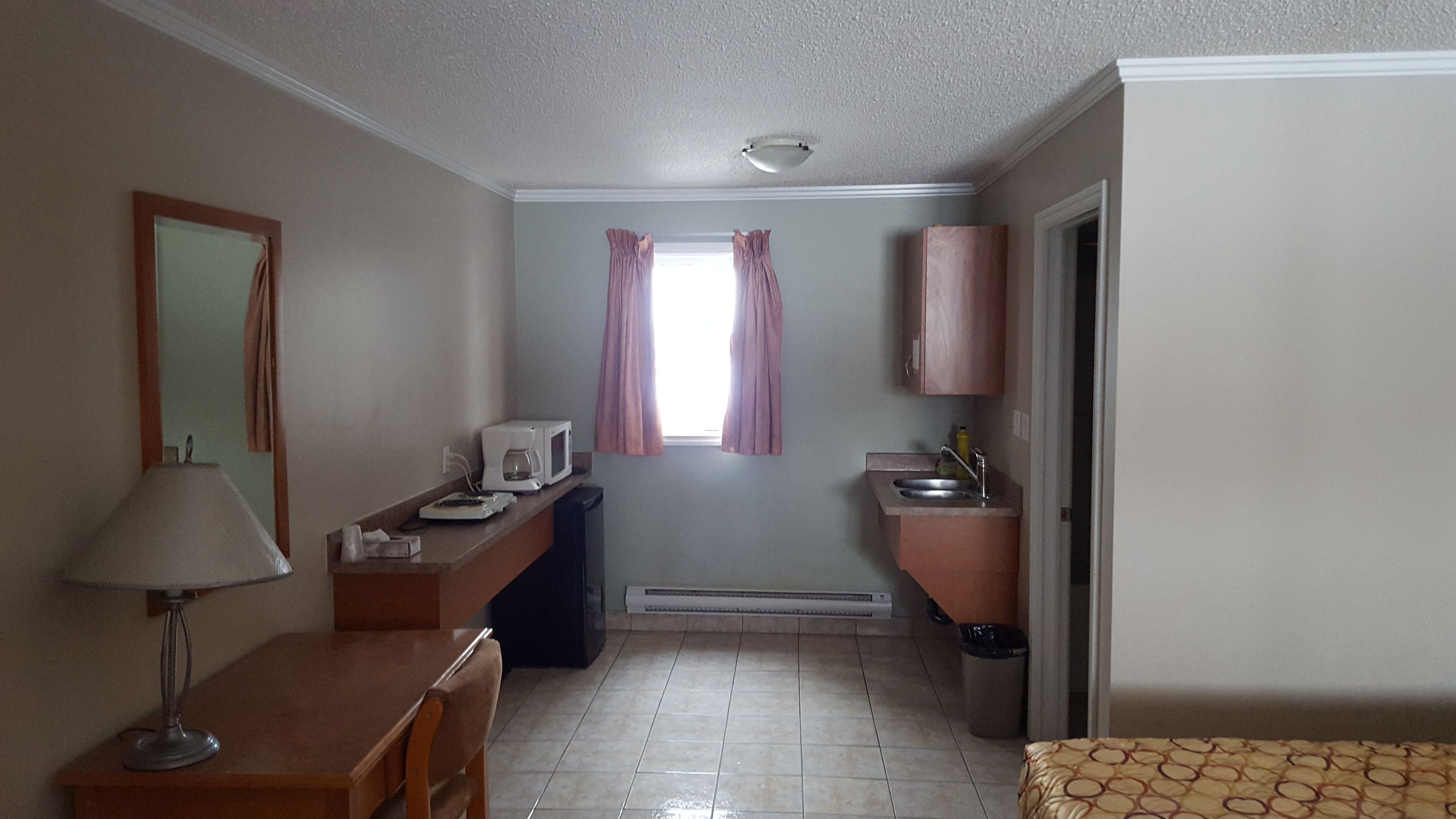 Una habitación de hotel compacta con kitchenette, comedor y baño.