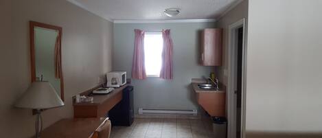 Una habitación de hotel compacta con kitchenette, comedor y baño.