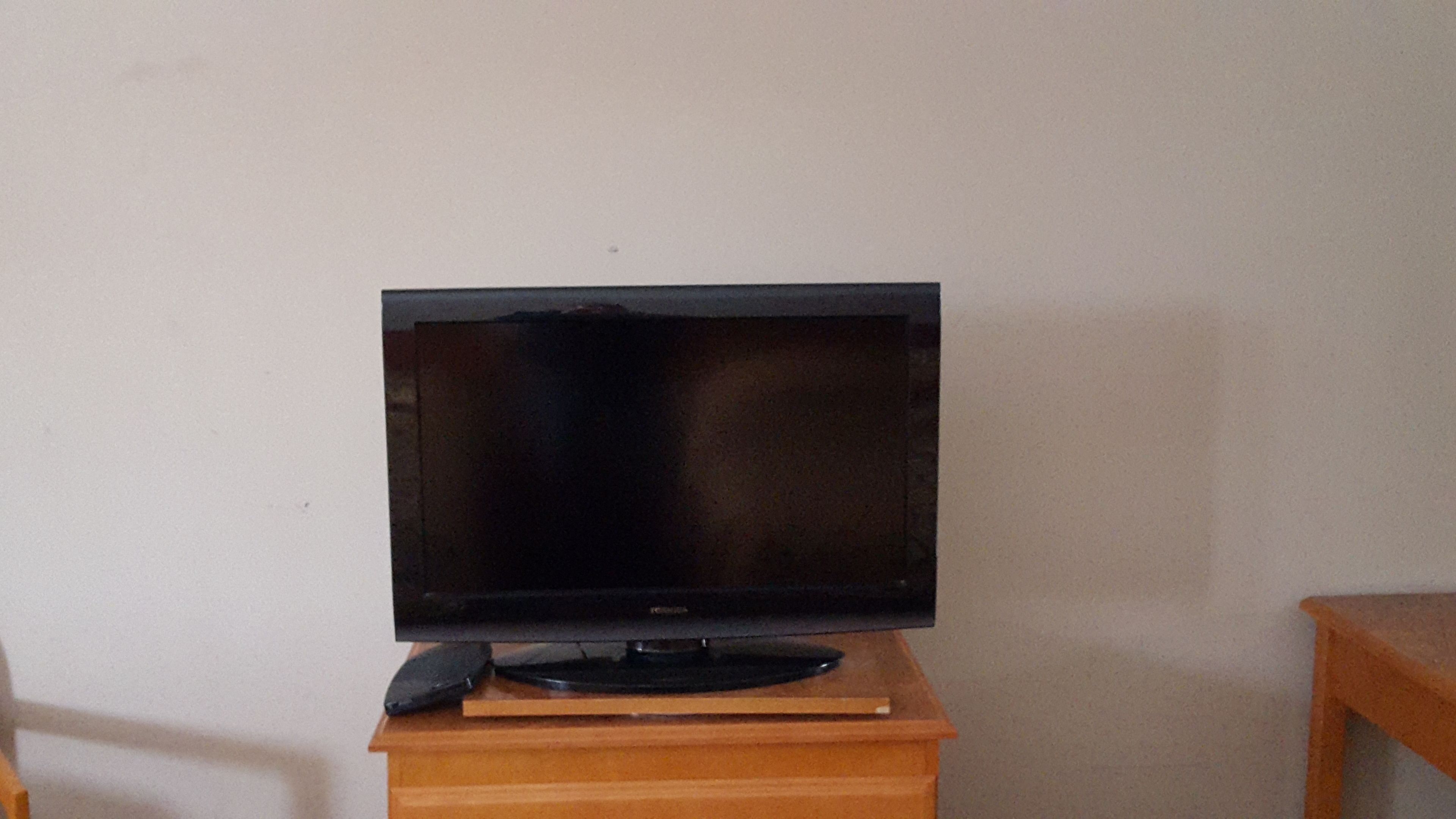 A flat-screen TV on a wooden stand in a room.