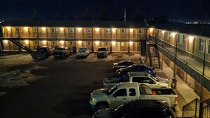 A multi-story motel with several parked cars in the driveway and a staircase leading to the upper floors. - Aspen Motor Inn (Drayton Valley)