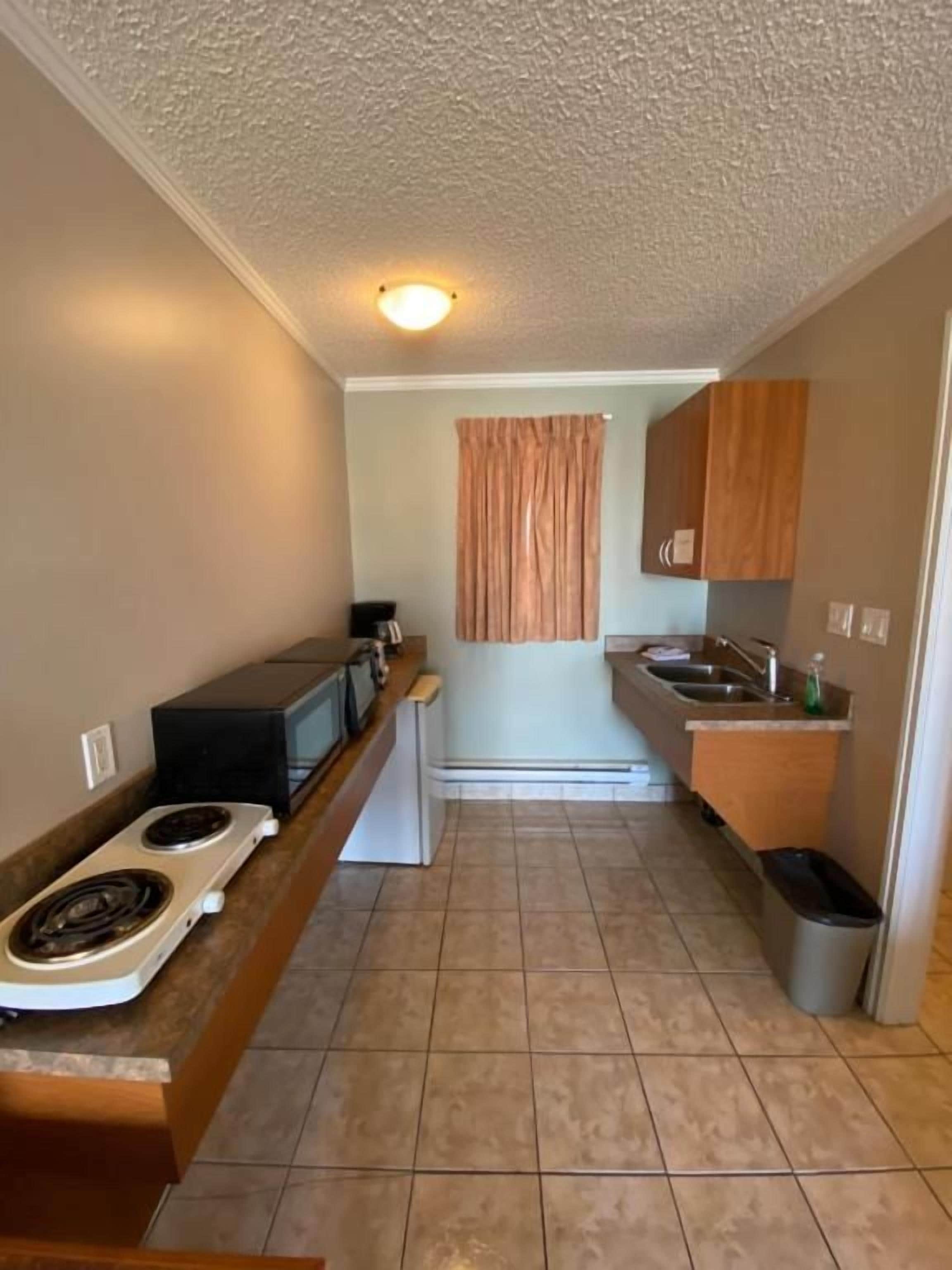 A compact kitchen with a stove, microwave, and sink.