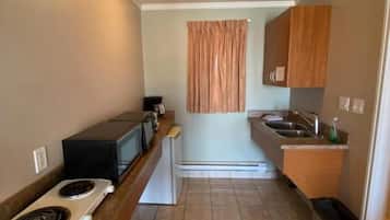 A compact kitchen with a stove, microwave, and sink.