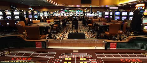 A casino floor with multiple gaming tables and slot machines.