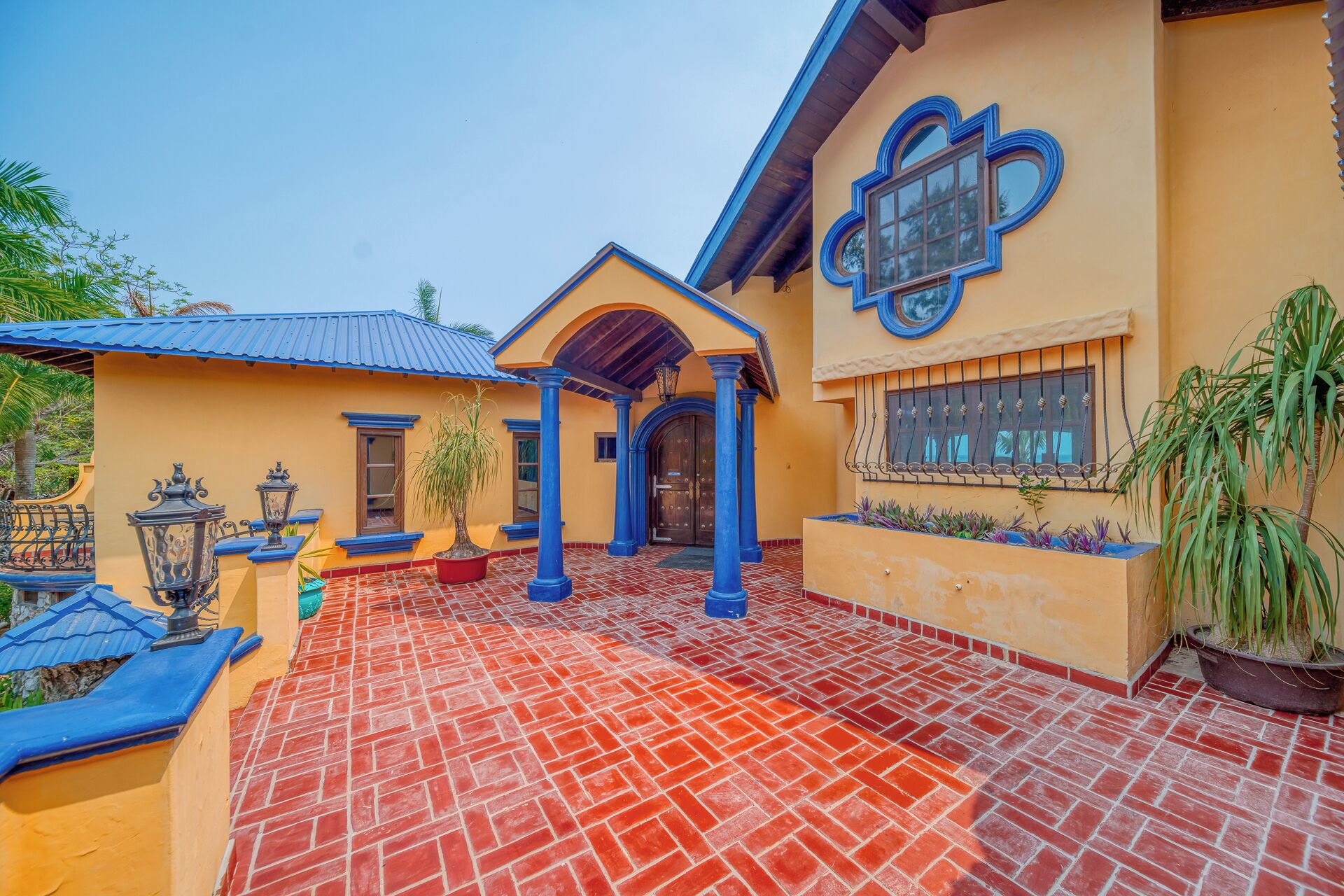 A traditional house with a tiled patio, a covered entrance, and decorative ironwork.
