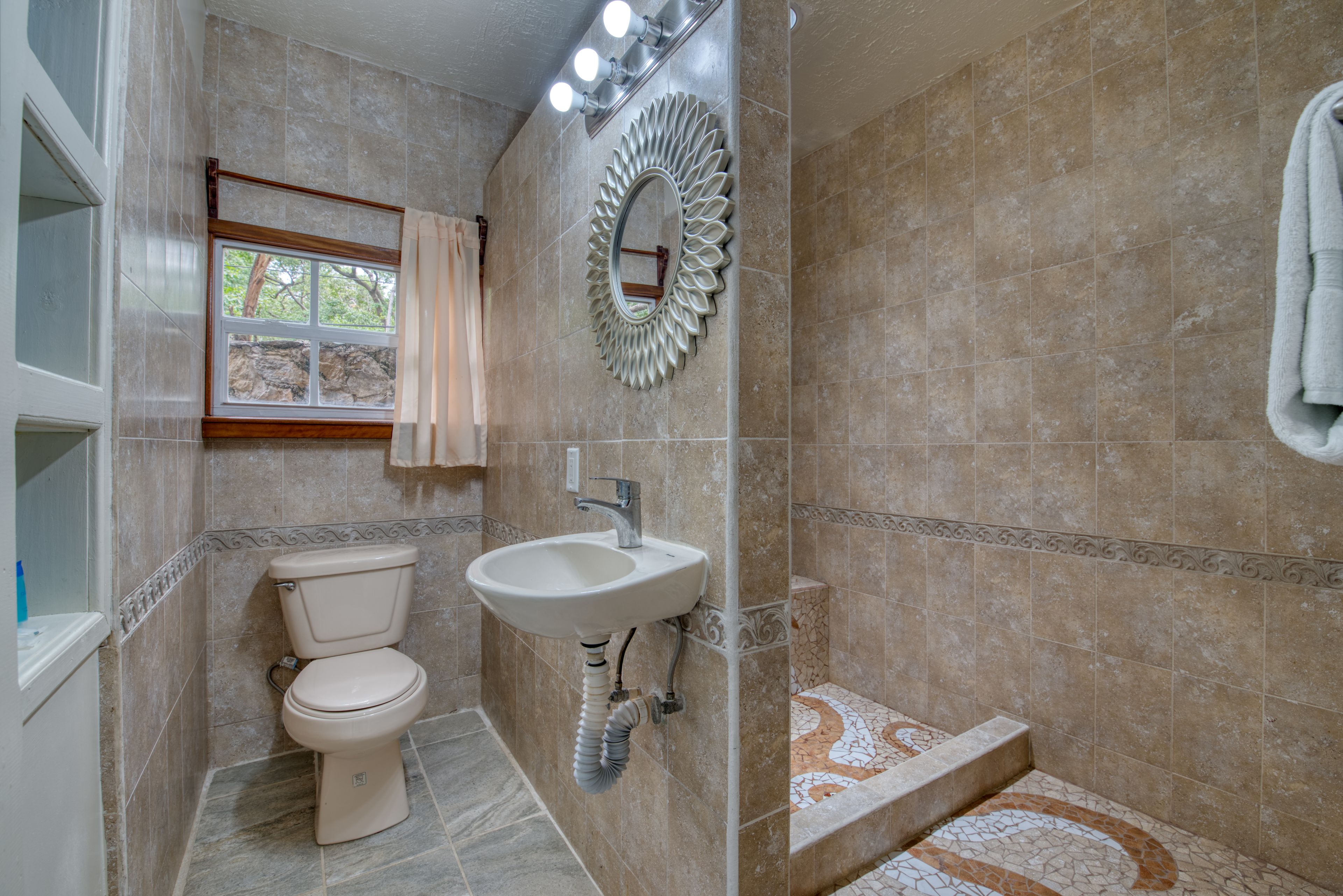 Une salle de bain comprenant des toilettes, un lavabo et un espace douche.