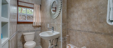 Un baño con inodoro, lavamanos y zona de ducha.