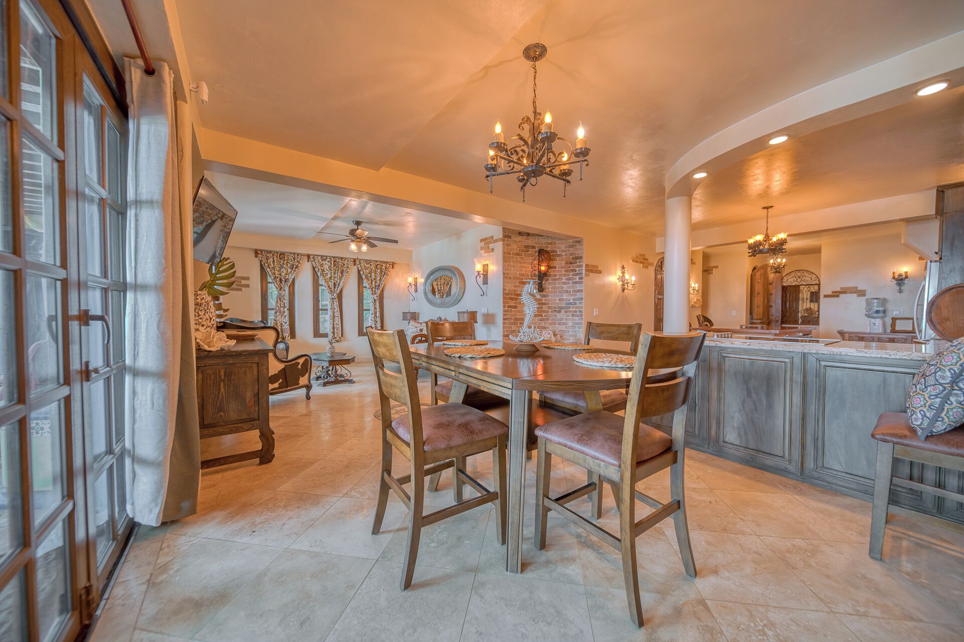 A spacious dining area with a large wooden table, several chairs, and a chandelier.