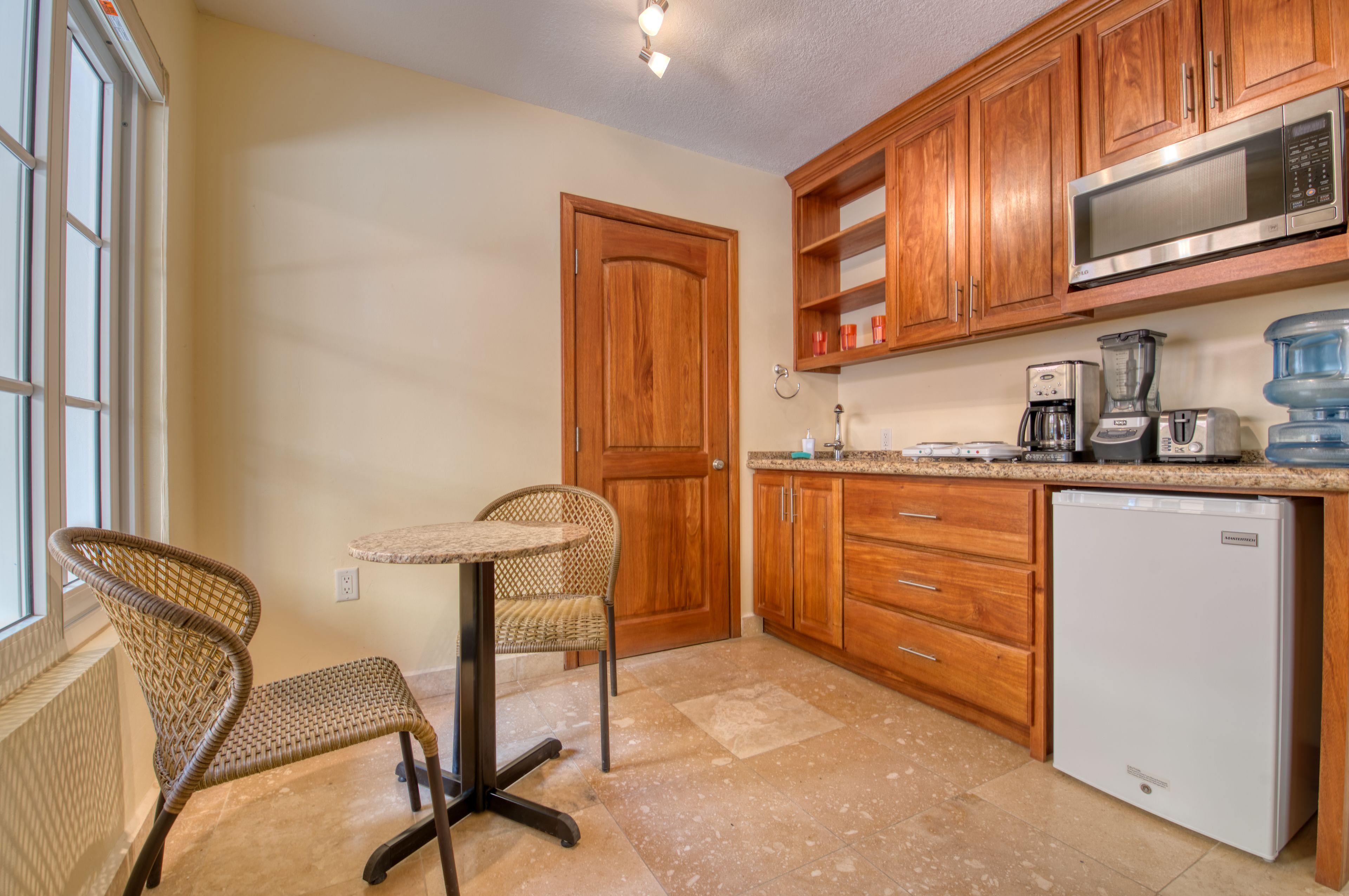 A kitchen with wooden cabinets, a microwave, a coffee maker, and a water dispenser.
