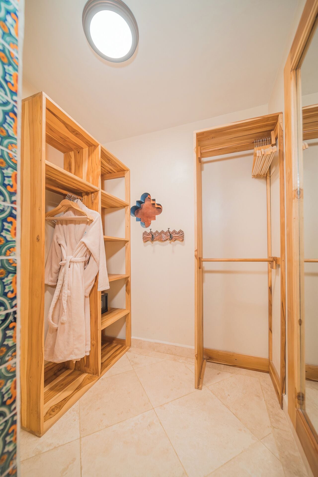 Un baño con estantes de madera, un perchero para bata y un perchero para toallas.