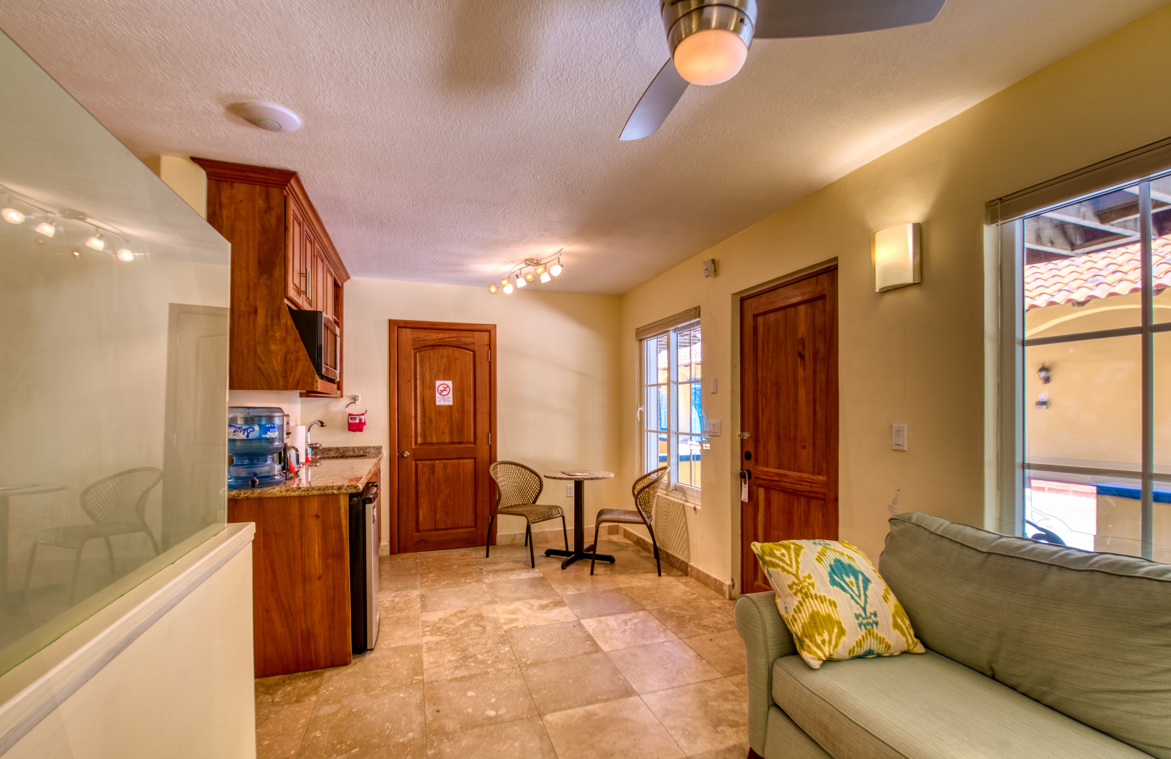 A compact kitchen with wooden cabinets, a built-in dishwasher, and a dining area with two chairs and a small table.