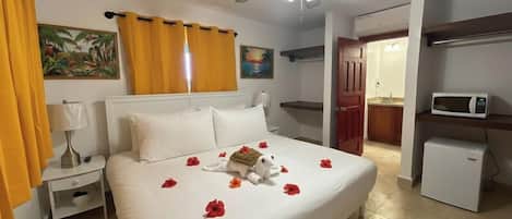 A hotel room with a bed, a ceiling fan, a microwave, and a small refrigerator.