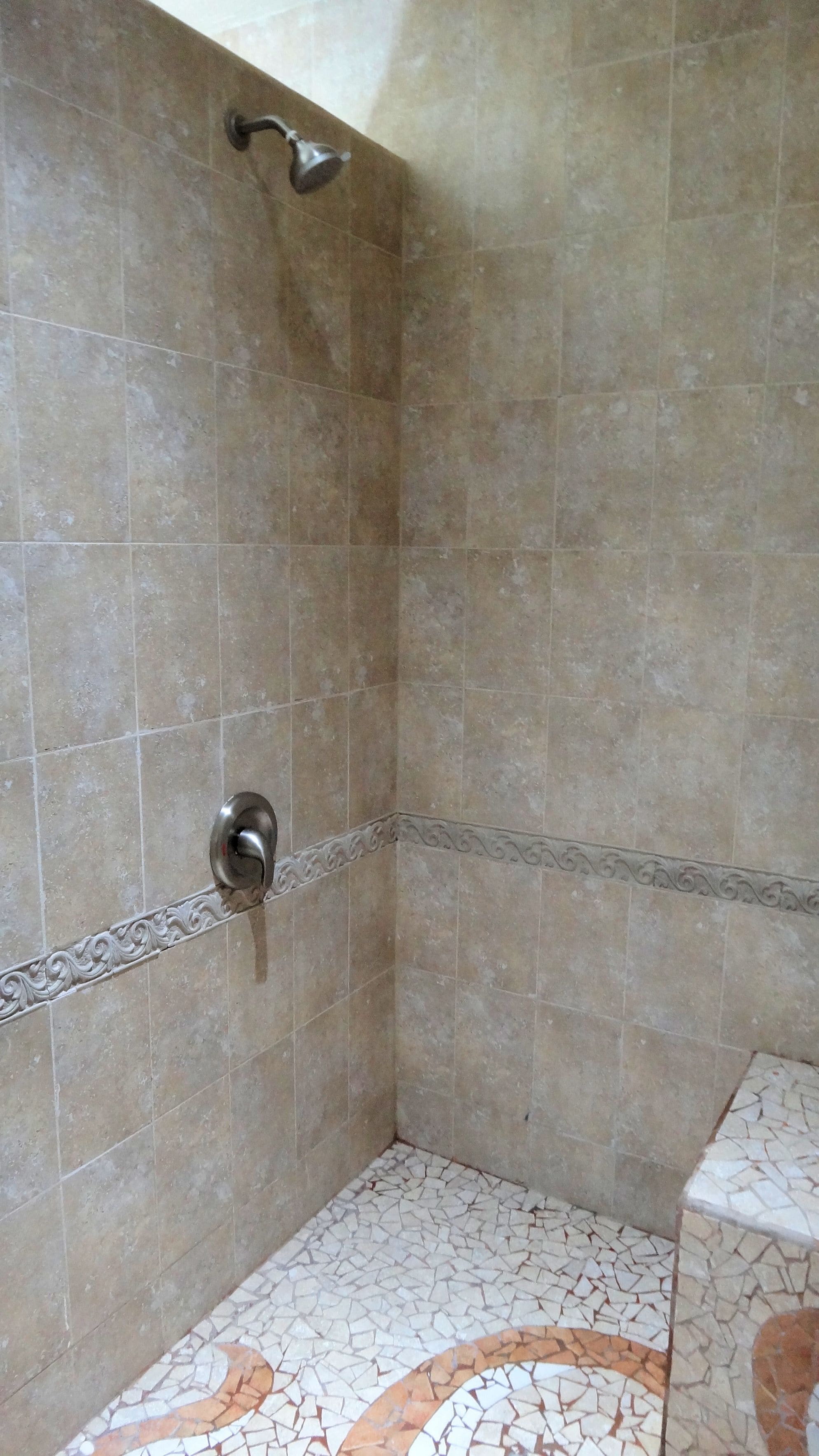 A shower area with tiled walls and floor, a showerhead, and a drain.