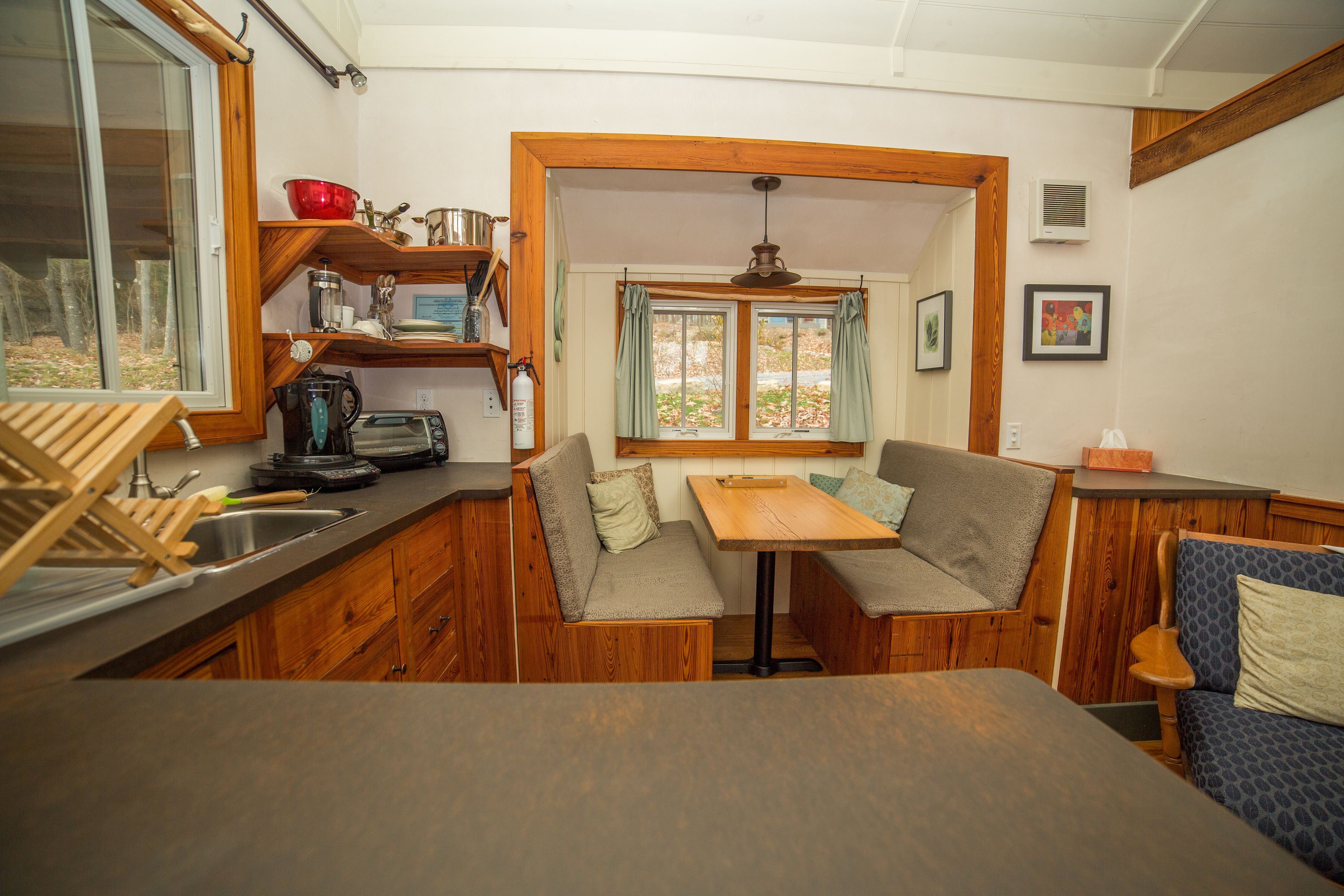 A compact kitchen with wooden cabinets, a sink, and a dining area with a bench and table.